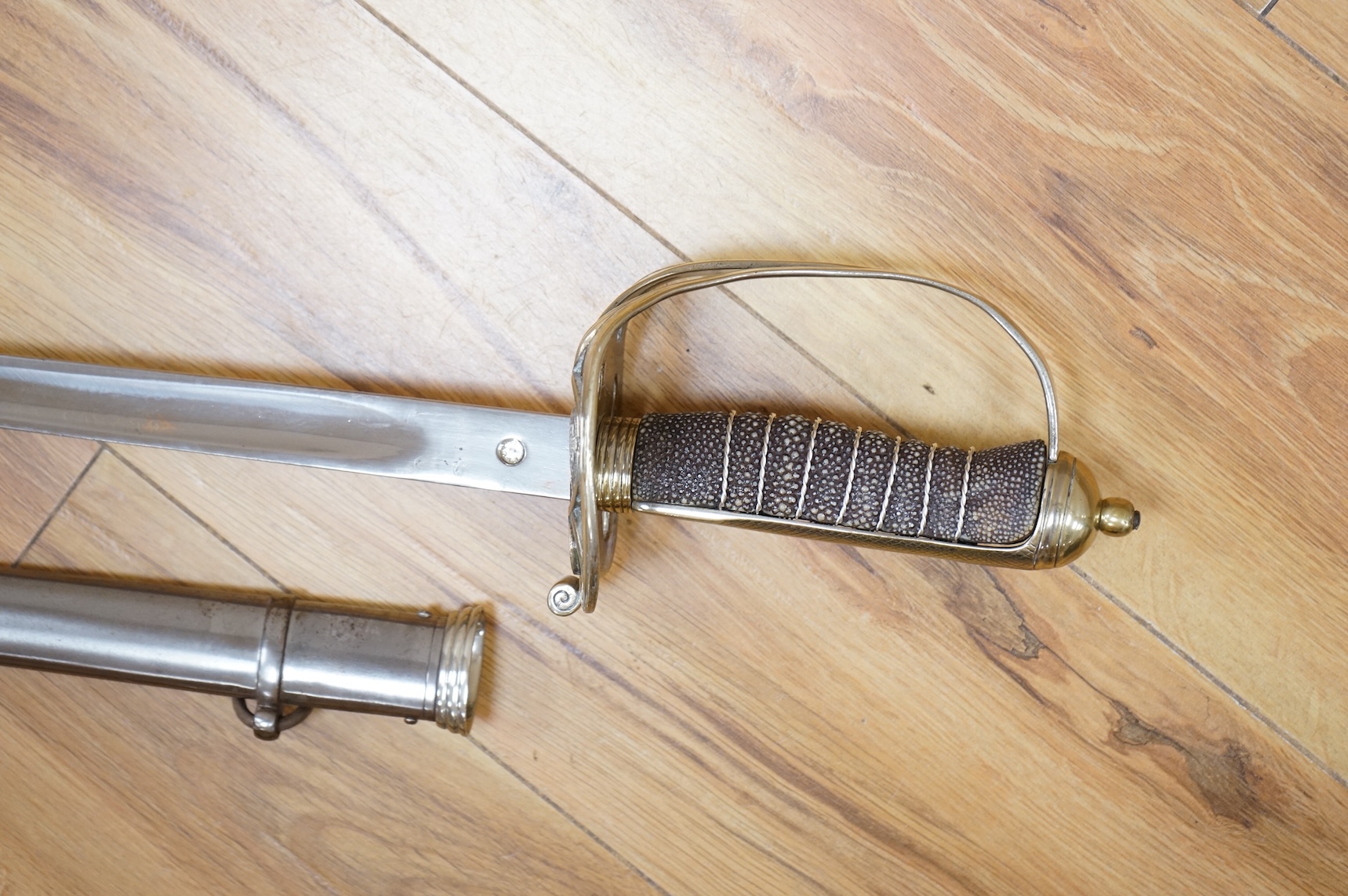 A post 1902, 1827 pattern Rifle Brigade officer’s dress sword, with regulation blade with traces of edge decoration, regulation nickel guard with crown strung bugle and wire bound fish skin covered grip, in its steel sca
